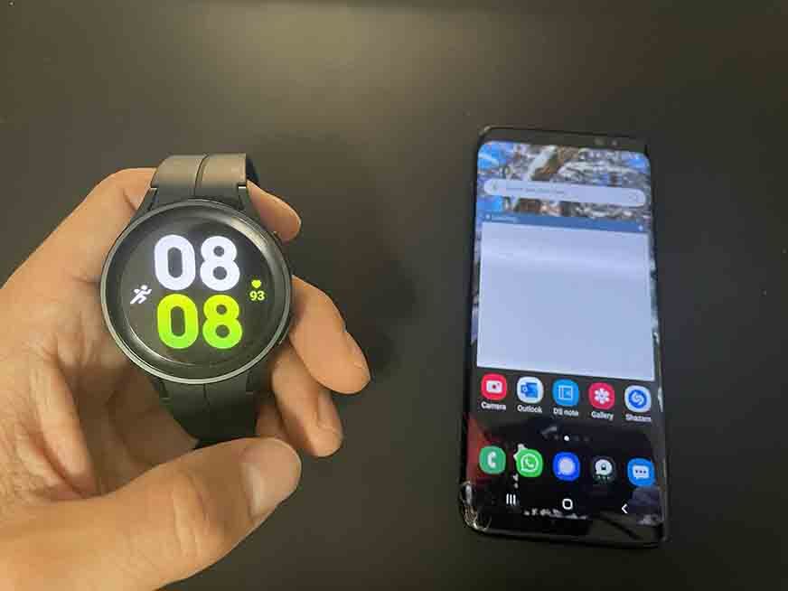 Galaxy Watch 5 рядом с мобильным телефоном.